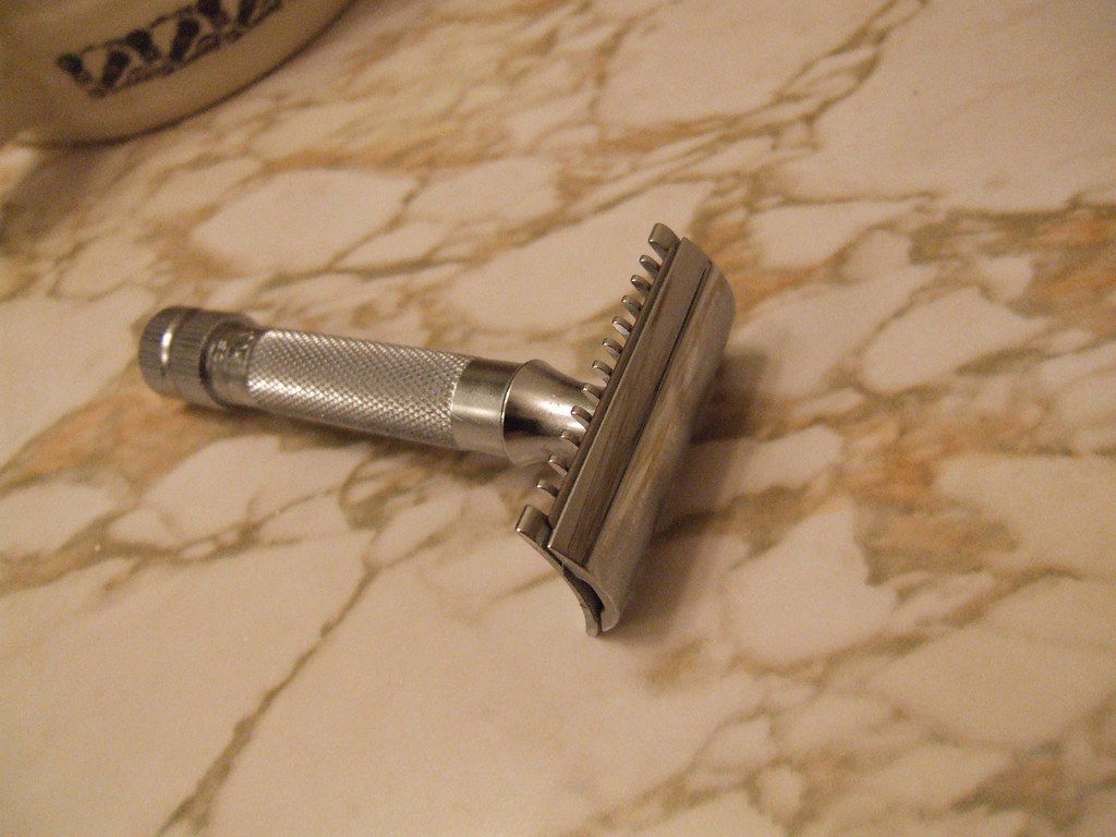 Traditional double-edge safety razor on a marble bathroom counter