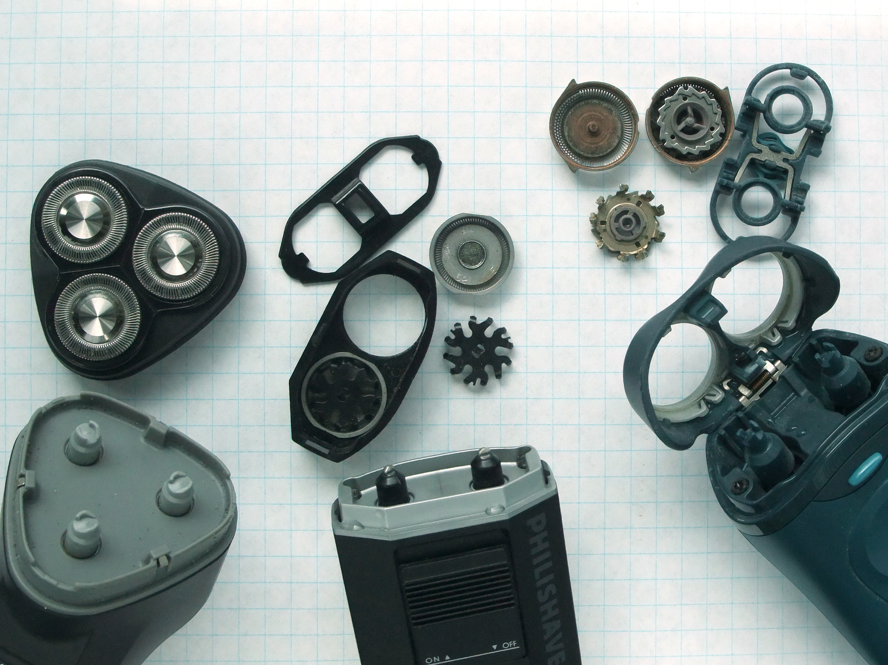 A rotary electric shaver disassembled, showing its three circular spinning cutter heads