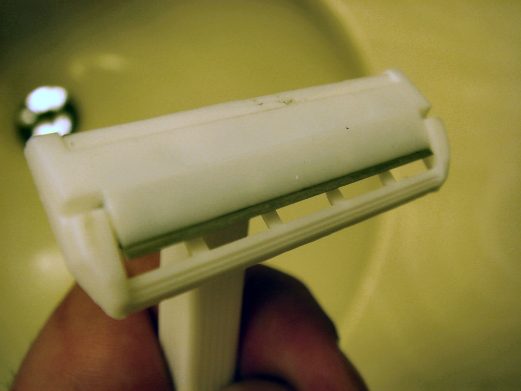 A cheap disposable razor over a sink, the kind that needs replacing often when you shave your head