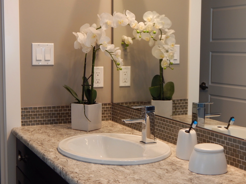 A tidy bathroom vanity with a clean sink and mirror, where a head shaver should be disinfected and stored