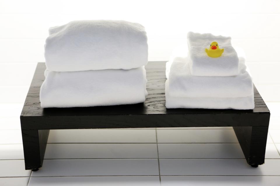 Clean white spa towels on a bench in a bright bathroom, illustrating a fresh scalp-care setup