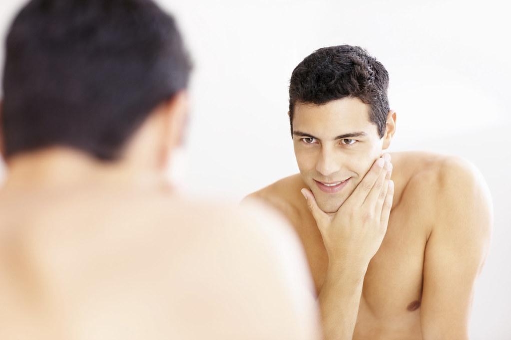 Reflection of a guy in the bathroom mirror after shaving