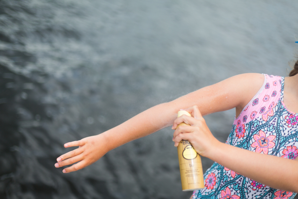 Spraying SPF sunscreen onto exposed skin before sun exposure