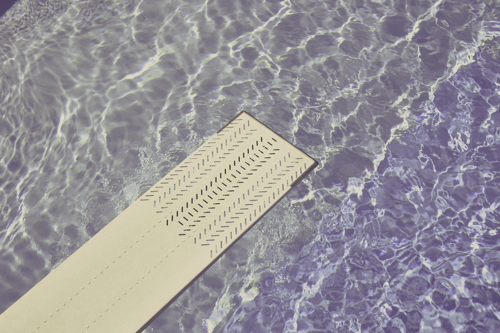 Crystal-clear chlorinated swimming pool water beside a diving board