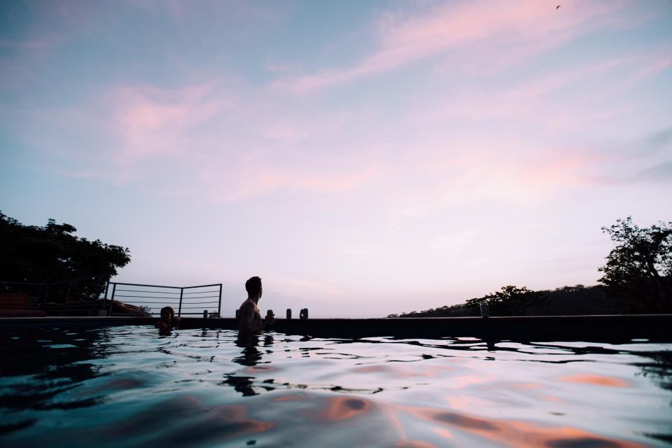 A man standing in a swimming pool at dusk