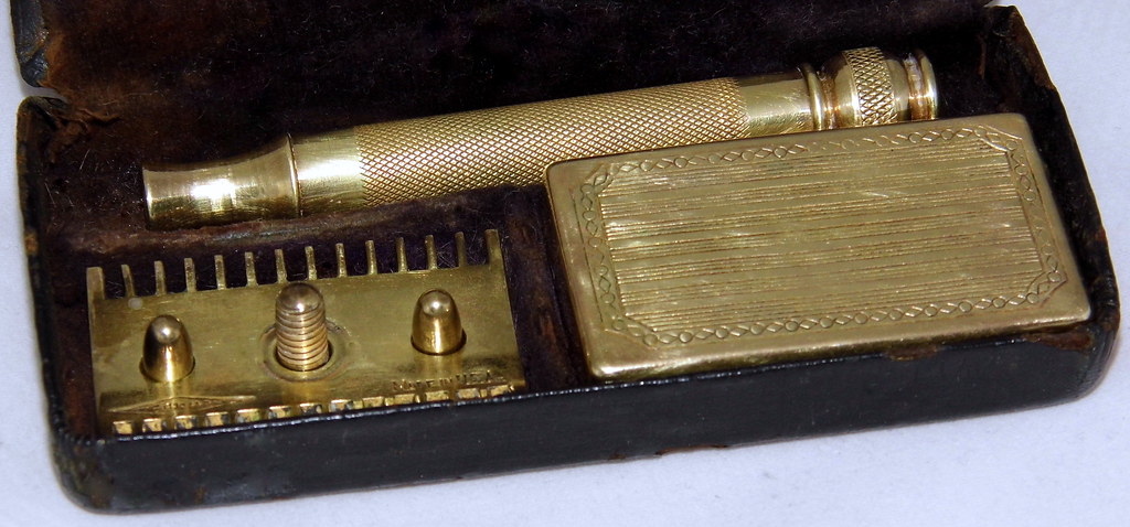 A vintage brass double-edge safety razor in its case, the classic wet-shaving tool for a bald head