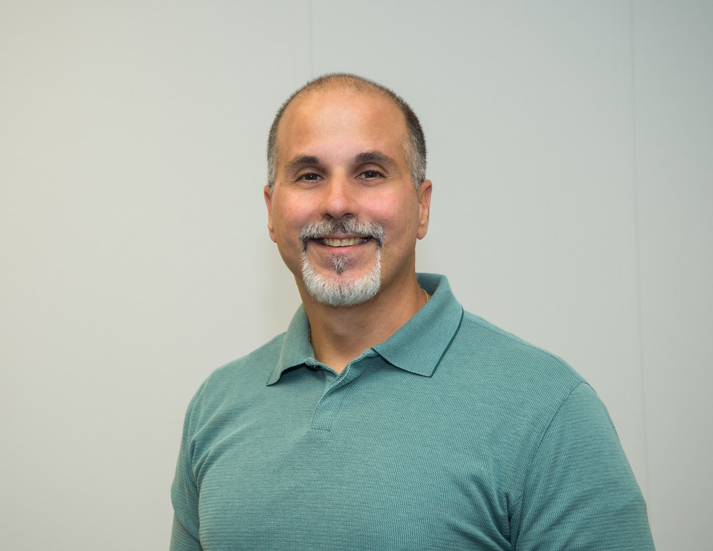 A middle-aged man with thinning, receding hair and a gray goatee, weighing whether to shave his head