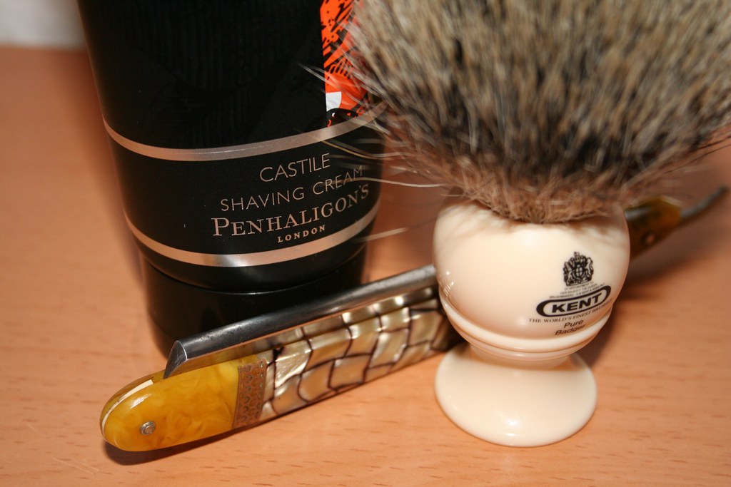 Shaving cream, a lather brush and a razor laid out as part of a head-shaving kit